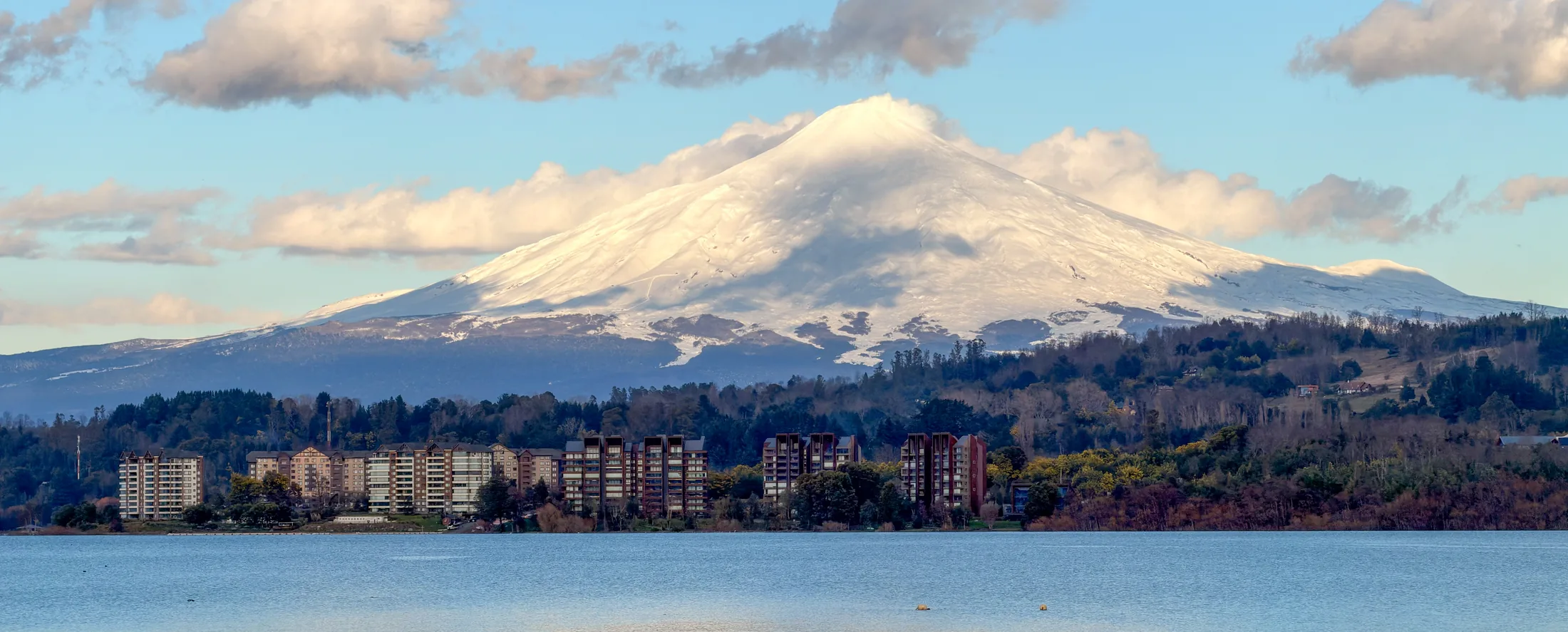 El volcán Villarrica y la costanera de la ciudad vistos desde la ribera del lago